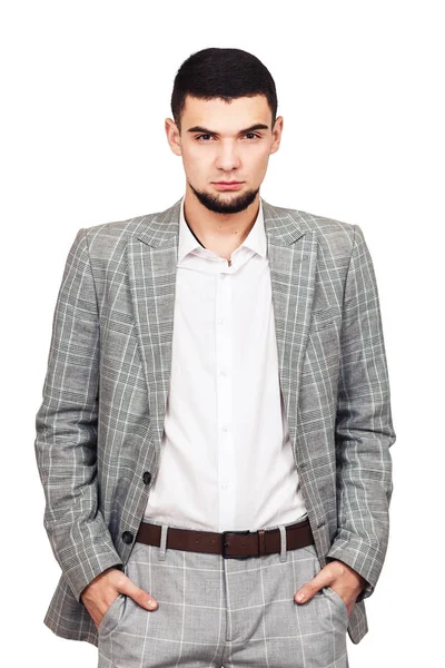 Elegantní mladý vousatý chlap v šedém obleku pózuje na bílém pozadí. — Stock fotografie