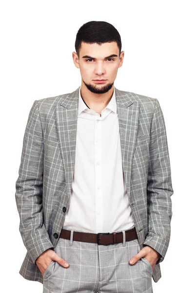 Elegante jovem barbudo cara em um terno cinza posando em um fundo branco . — Fotografia de Stock