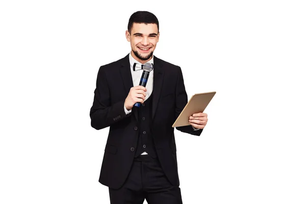 Elegante hombre elegante en un traje negro con un micrófono y una tableta en sus manos —  Fotos de Stock