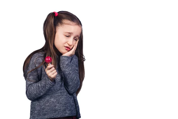 Маленькая грустная девочка с красным леденцом в руках, чьи зубы болят . — стоковое фото