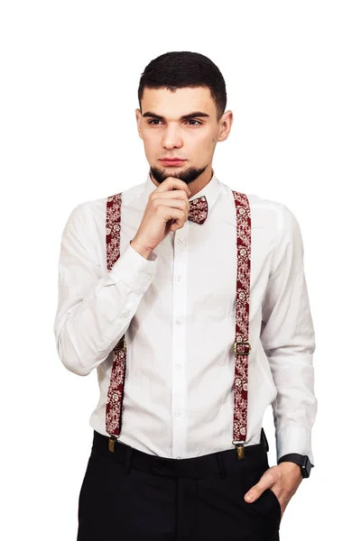 Snygga unga skäggiga killen i skjorta, byxor och hängslen poserar på en vit bakgrund — Stockfoto