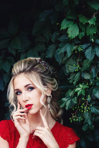 Atractiva joven rubia en vestido rojo posando cerca de un viñedo salvaje . — Foto de Stock