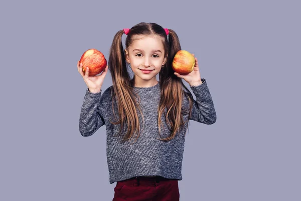 Schattig meisje houdt twee appels in haar handen en glimlacht. — Stockfoto