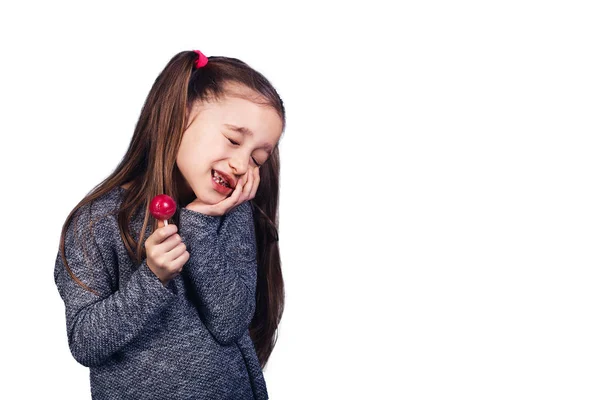 Маленькая грустная девочка с красным леденцом в руках, чьи зубы болят . — стоковое фото