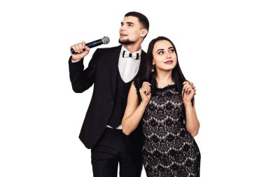 siyah bir takım elbise içinde sakallı adam elinde bir mikrofon ve bir siyah gece elbisesi içinde güzel bir kız ile