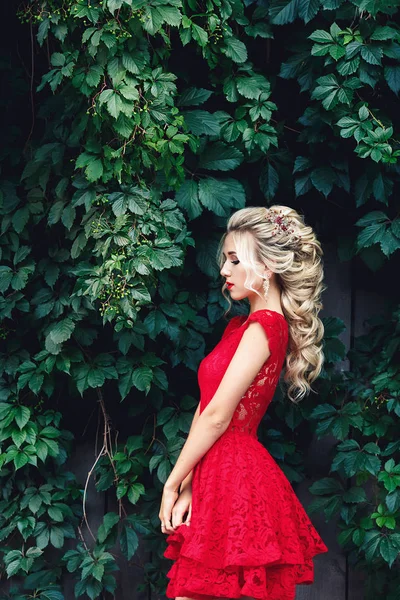 Atractiva joven rubia en vestido rojo posando cerca de un viñedo salvaje . — Foto de Stock