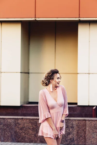 Atractiva joven en un vestido corto de color rosa posando cerca de un hermoso edificio . — Foto de Stock