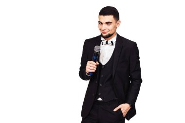 şık zarif neşeli adam siyah bir takım elbise içinde bir mikrofon elinde gözleri haçlar. beyaz izole