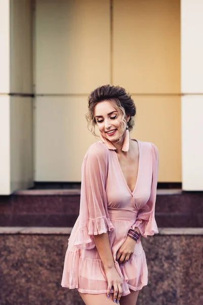 Atractiva joven en un vestido corto de color rosa posando cerca de un hermoso edificio . — Foto de Stock