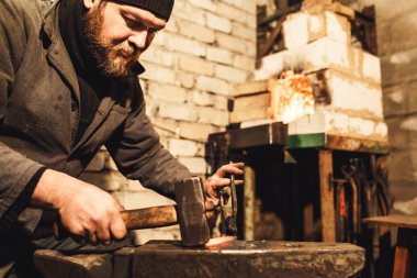 Demirci bir sıcak metal örs üzerinde çekiçle uydurandan..