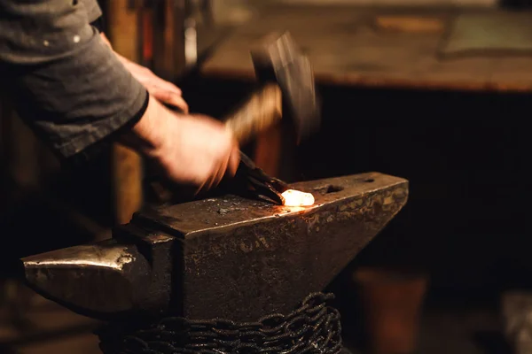 The blacksmith manually forging the red-hot metal on the anvil in smithy. — Stock Photo, Image