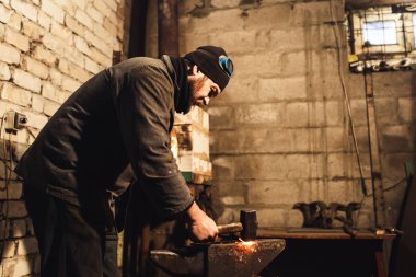 El ile örs ve uçan kırmızı-sıcak metal dövme demirci kıvılcım.