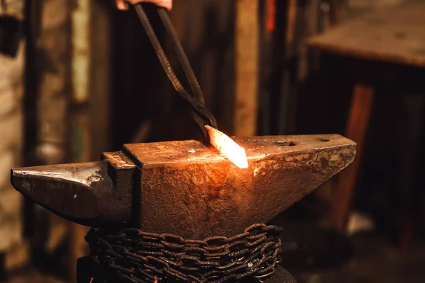 De smid smeden handmatig de gloeiende metalen op het aambeeld in smithy. — Stockfoto