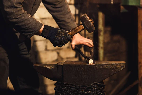 The blacksmith manually forging the red-hot metal on the anvil in smithy. — Stock Photo, Image