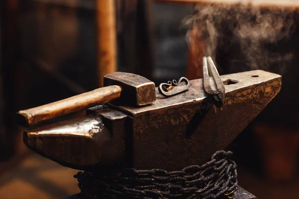 Närbild av en smed städet med en hammare, tång och firesteel. — Stockfoto