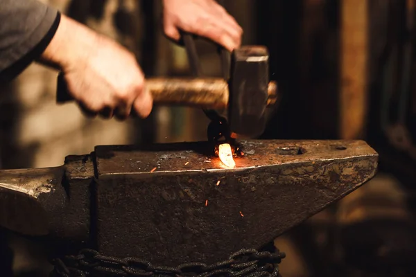 The blacksmith manually forging the red-hot metal on the anvil in smithy with spark fireworks. — Stock Photo, Image