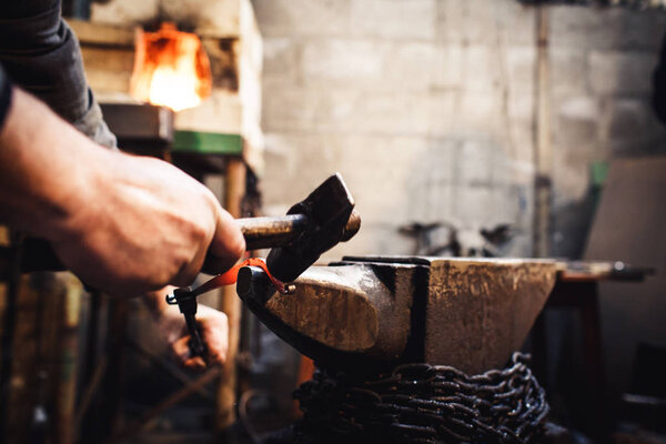 blacksmith makes an artistic forging of hot metal on the anvil.