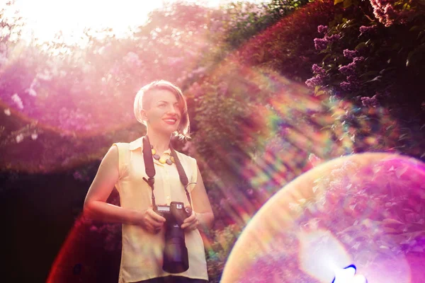 Nádherné jarní. dívka fotograf má příroda a slunečním světlem mezi kvetoucí šeřík. — Stock fotografie