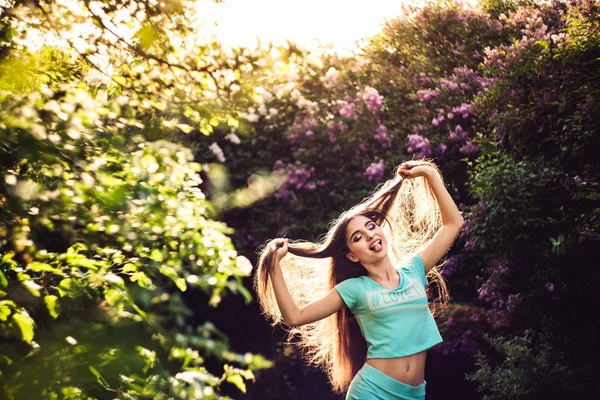 Prachtige lente. Een mooi jong meisje geniet van natuur en zonlicht onder de bloeiende lila. — Stockfoto
