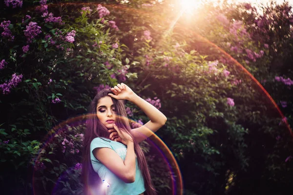 Maravillosa primavera. Una hermosa joven disfruta de la naturaleza y la luz del sol entre la floreciente lila . —  Fotos de Stock