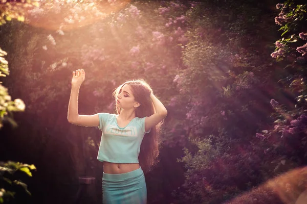 Nádherné jarní. Krásná mladá dívka má příroda a slunečním světlem mezi kvetoucí šeřík. — Stock fotografie