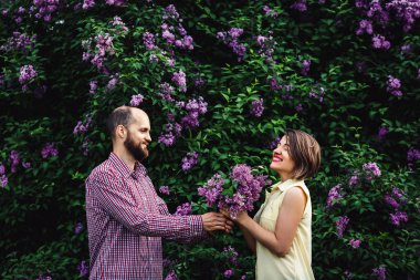 Genç bir kız Lila çiçek bir buket doğa verir adam sakallı.