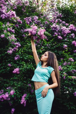 Harika bahar. Sevimli genç kız doğa arasında çiçek açması leylak sahiptir ve bir buket tutar.