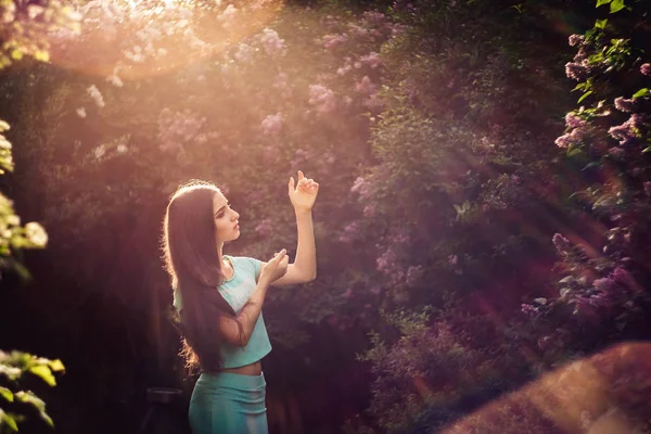 Maravilhosa primavera. Uma bela jovem goza de natureza e luz solar entre o lilás florescente . — Fotografia de Stock