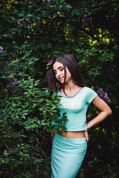 Harika bahar. Sevimli genç kız doğa Eflatun çiçek açan yakınındaki poz.