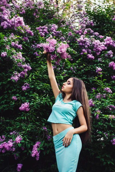 Harika bahar. Sevimli genç kız doğa arasında çiçek açması leylak sahiptir ve bir buket tutar.