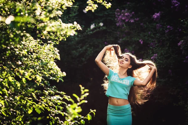 Maravilhosa primavera. Uma bela jovem goza de natureza e luz solar entre o lilás florescente . — Fotografia de Stock