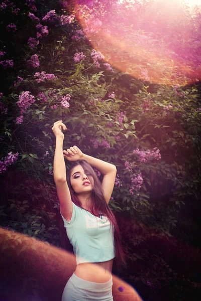 Maravillosa primavera. Una hermosa joven disfruta de la naturaleza y la luz del sol entre la floreciente lila . —  Fotos de Stock