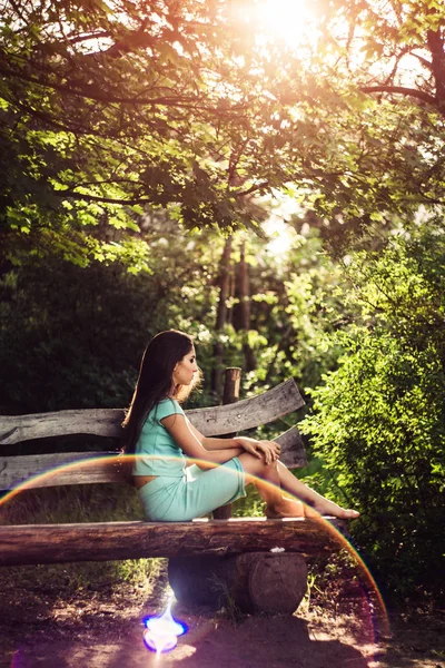 Splendida primavera. Bella ragazza gode la natura e la luce del sole seduto su una panchina di legno nel parco . — Foto Stock