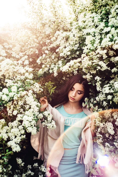 Maravilhosa primavera. Menina bonita goza de natureza e luz solar entre a spirea florescente . — Fotografia de Stock