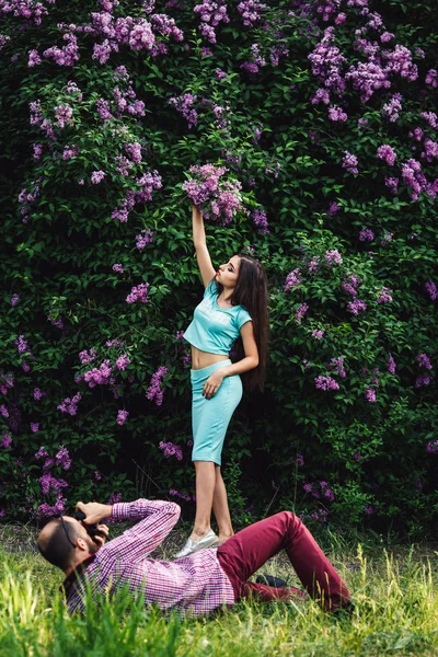 Fotograf strzela dziewczyna w parku wśród kwitnących liliowy. — Zdjęcie stockowe