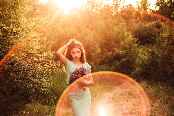 Prachtige lente. Een mooi jong meisje geniet van natuur en zonlicht onder de bloeiende lila. — Stockfoto