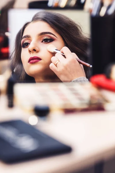 process of making makeup. Makeup artist works with brush on model's face.