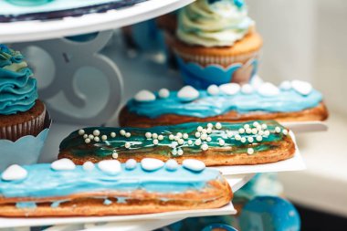 turkuaz krema ve cupcakes yakın çekim şenlikli masada ile lezzetli eclairs.