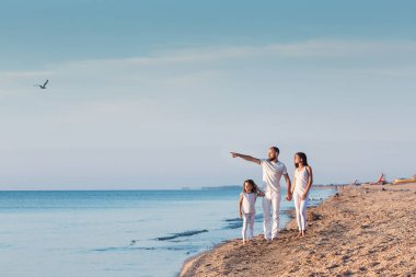 aile şafakta sahilde yürüyor.