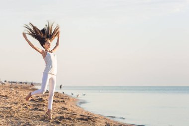 sevimli genç kız sahilde yürür ve zevk için atlar.