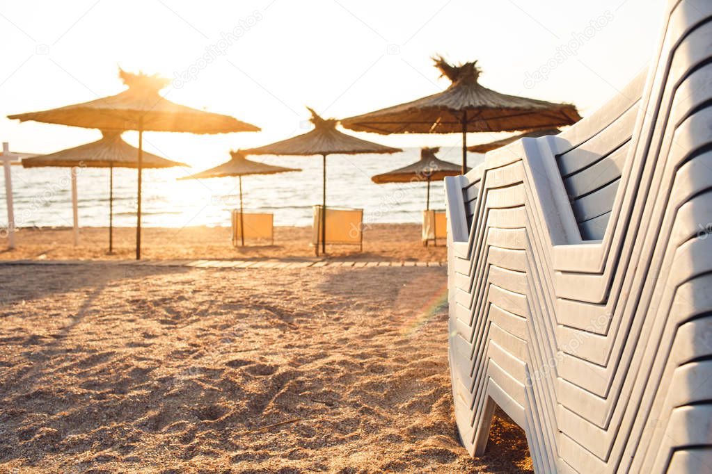 reed beach umbrellas and sunbeds on sandy seashore in sun.