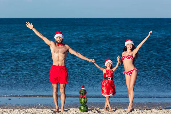 Young friendly family fun celebrating summer Christmas on beach.