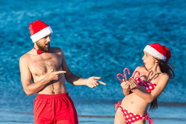 サンタの帽子の陽気な男と女の子はクリスマスロリポップを保持しています. — ストック写真