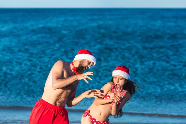 Cheerful man and girl in Santa hats are holding Christmas lollipops. — Stock Photo, Image