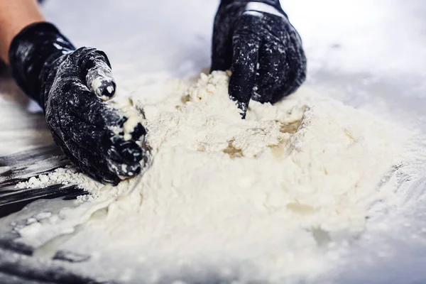 Baker's hands in black gloves knead the dough. — Stock Photo, Image