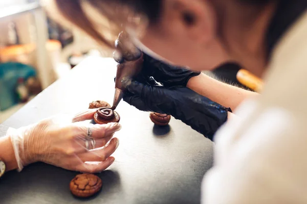 Banketbakker perst chocolade room uit een banketbakje op koekjes. chocoladekoekjessandwich maken. — Stockfoto