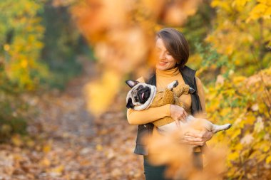 Gülümseyen kız güz köpeğini parkta tutuyor..