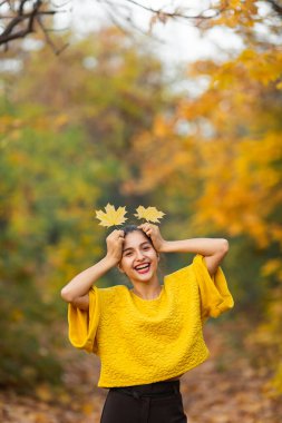 Sonbahar akçaağaç yapraklı neşeli kadın portresi parkta.