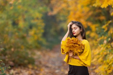 Sonbahar akçaağaç yapraklı neşeli kadın portresi parkta.