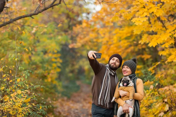 Uśmiechnięta Młoda Para Psem Świeżym Powietrzu Jesiennym Parku Robi Selfie — Zdjęcie stockowe